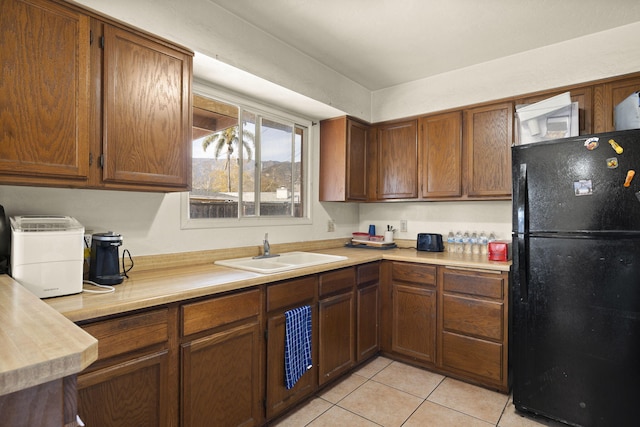 kitchen featuring light tile patterned flooring, sink, and black fridge