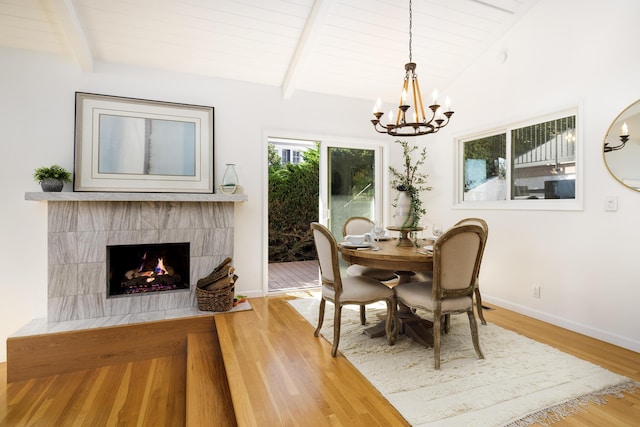 dining area featuring vaulted ceiling with beams, hardwood / wood-style floors, a fireplace, wooden ceiling, and a chandelier