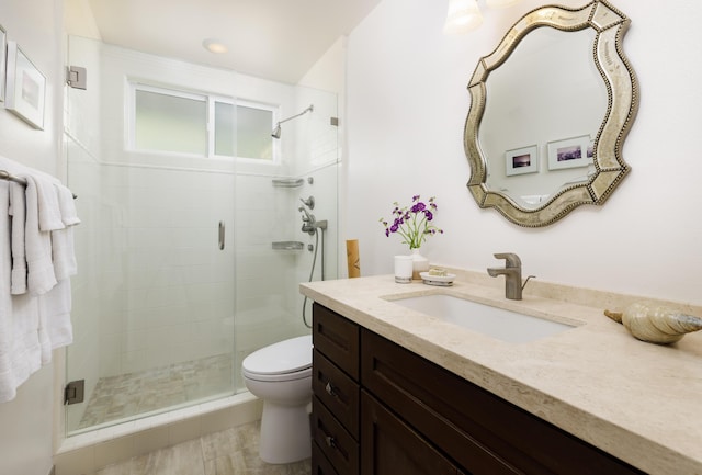 bathroom with an enclosed shower, vanity, and toilet