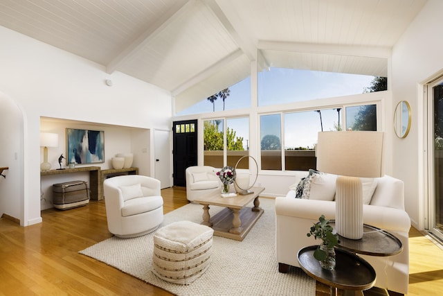 living room featuring beam ceiling, high vaulted ceiling, and wood finished floors