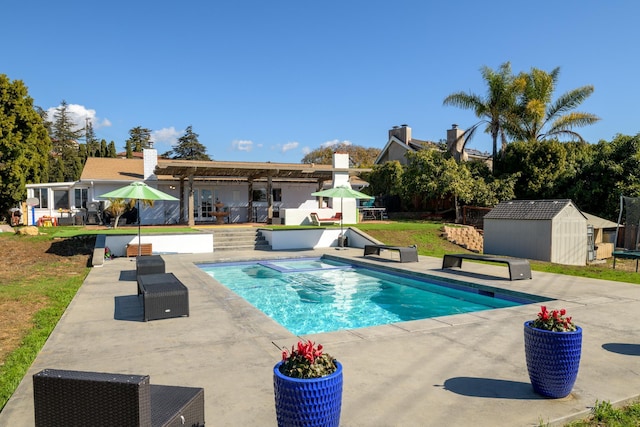 view of swimming pool with a patio and a storage shed