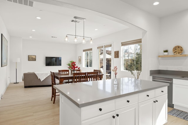 kitchen featuring pendant lighting, dishwasher, white cabinetry, a kitchen island, and light wood-type flooring