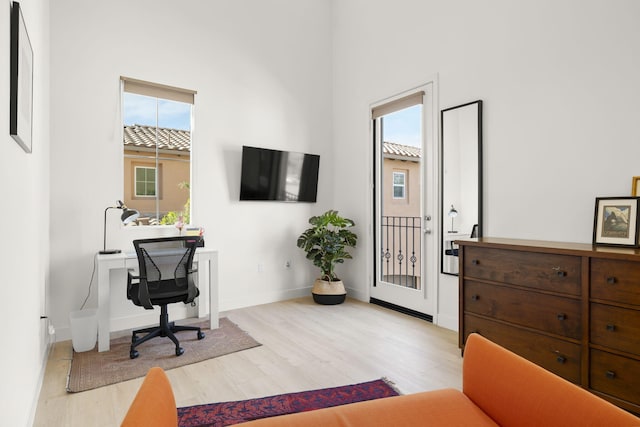 office area with a high ceiling, a wealth of natural light, and light hardwood / wood-style floors