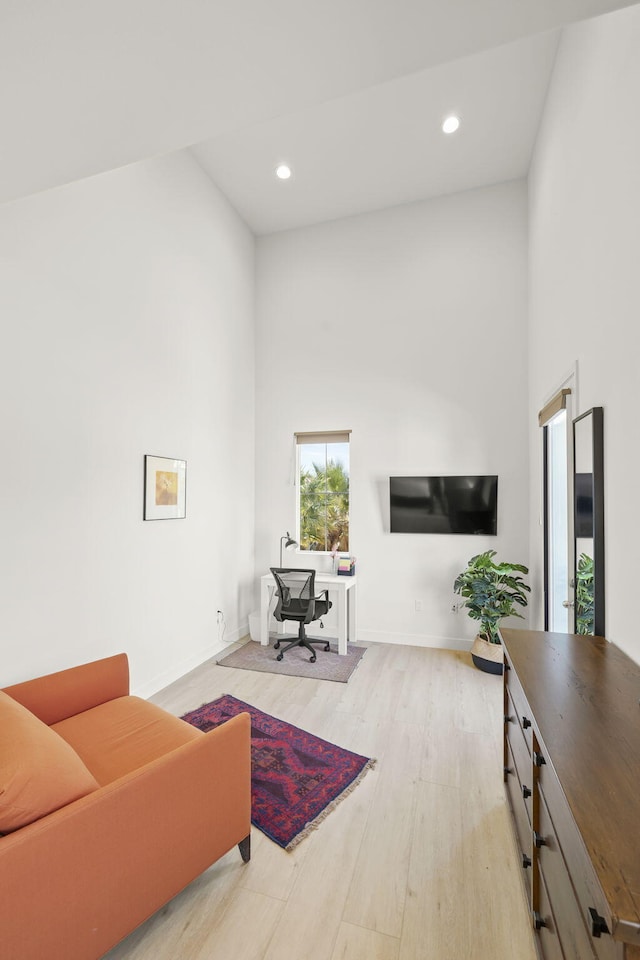 office area featuring a towering ceiling and light hardwood / wood-style flooring