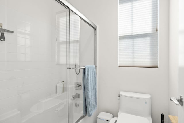 bathroom featuring toilet and a shower with shower door