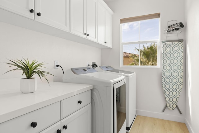 laundry room with cabinets, light hardwood / wood-style floors, and washer and dryer