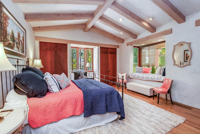 bedroom featuring lofted ceiling with beams and light hardwood / wood-style flooring