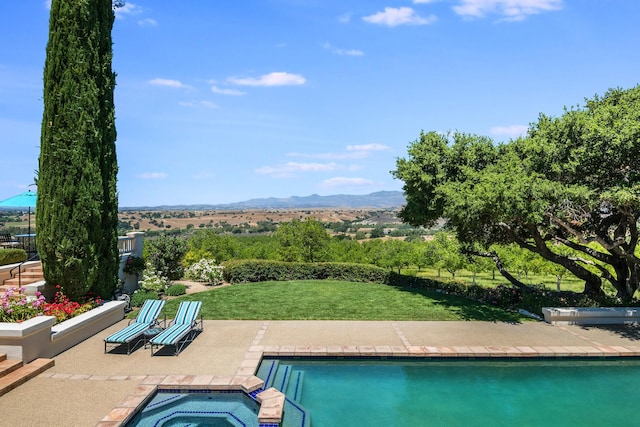 view of pool featuring an in ground hot tub, a mountain view, a patio, and a lawn