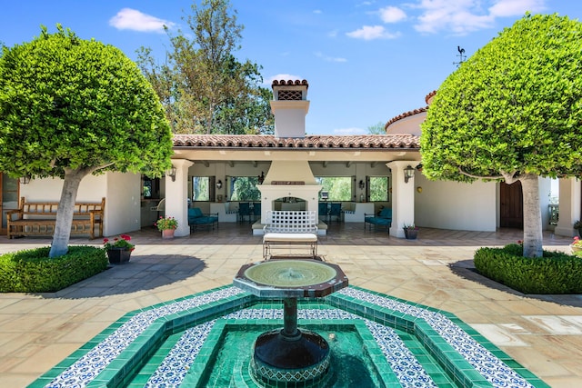 back of house featuring a patio, exterior fireplace, and an in ground hot tub