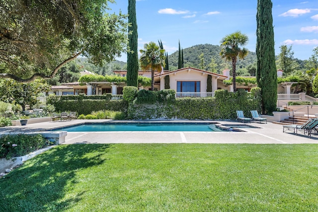 view of swimming pool featuring a yard, a mountain view, and a patio area