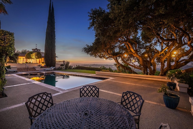 pool at dusk with a patio