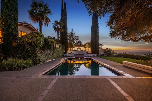 pool at dusk featuring a patio area