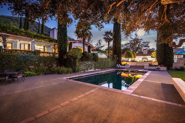 pool at dusk featuring a patio area