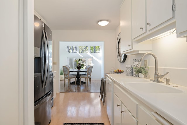 kitchen with light wood-type flooring, white cabinets, stainless steel fridge, sink, and white dishwasher