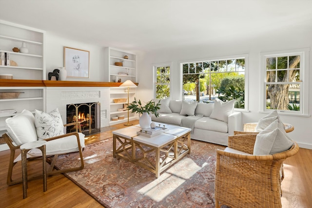 interior space featuring light hardwood / wood-style floors, a brick fireplace, and built in features