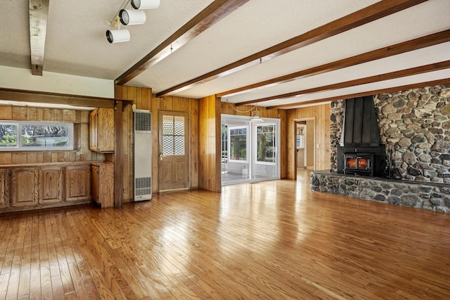 2385 Janin Pl, Solvang, CA 93463 - unfurnished living room with beam ceiling, wooden walls, light hardwood / wood-style floors, a textured ceiling, and a wood stove