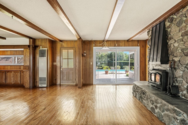 2385 Janin Pl, Solvang, CA 93463 - unfurnished living room featuring beamed ceiling, wooden walls, hardwood / wood-style floors, and a wood stove
