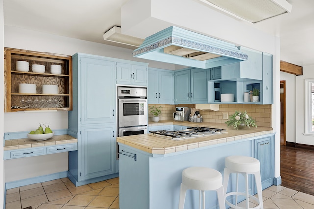 2385 Janin Pl, Solvang, CA 93463 - kitchen featuring light tile patterned flooring, tile countertops, a kitchen bar, stainless steel appliances, and blue cabinetry