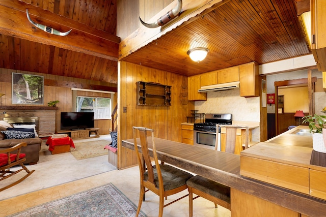 kitchen with wooden walls, sink, stainless steel range with gas stovetop, wooden ceiling, and beam ceiling