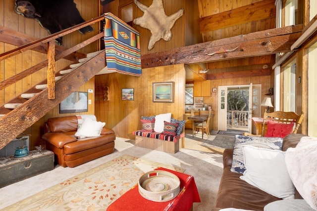 living room featuring a towering ceiling, wooden walls, and carpet floors