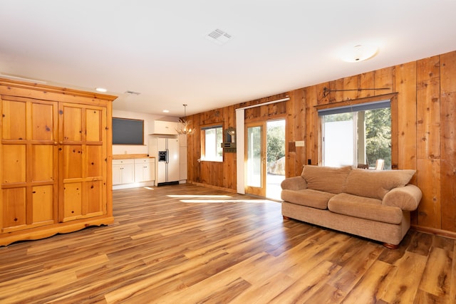 living room with light hardwood / wood-style floors and wood walls