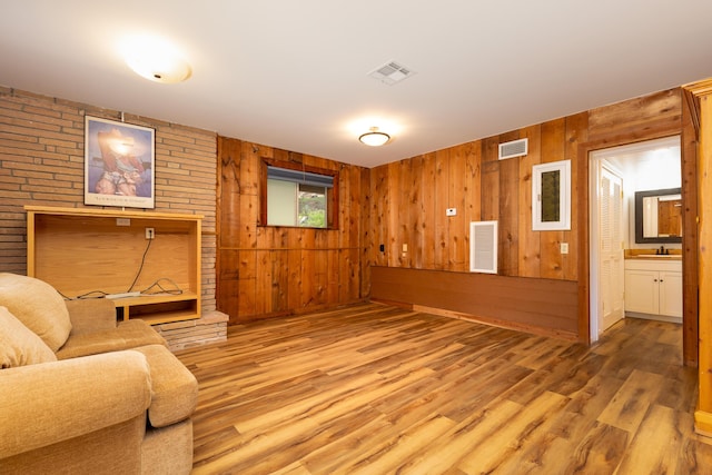 sitting room featuring sink, wooden walls, and hardwood / wood-style floors