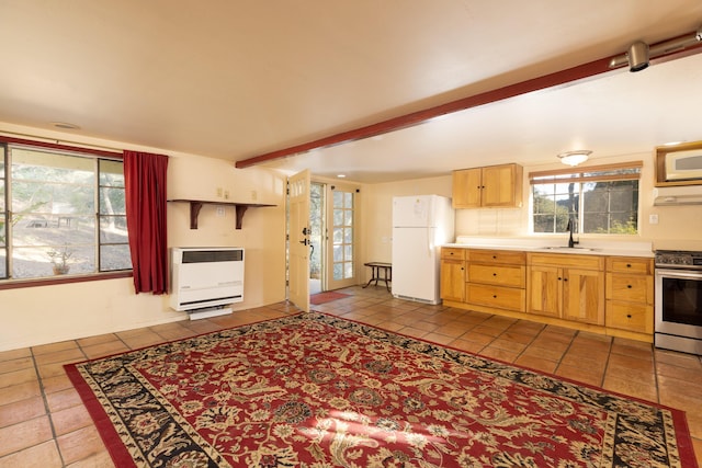 kitchen with heating unit, white appliances, beamed ceiling, and a healthy amount of sunlight