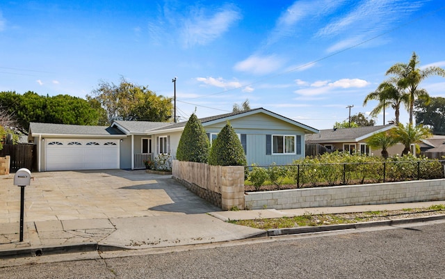 single story home with driveway, a fenced front yard, and an attached garage