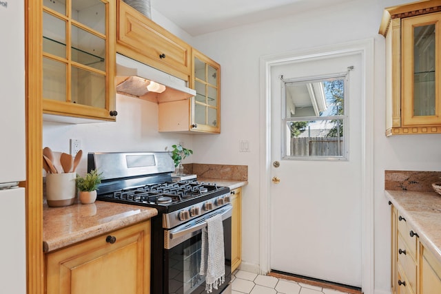 kitchen featuring glass insert cabinets, under cabinet range hood, light brown cabinets, and stainless steel gas range oven