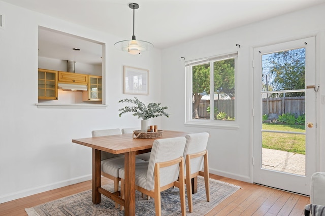 dining area with light wood-type flooring and baseboards