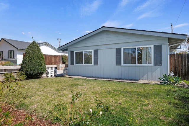 rear view of house with fence and a lawn