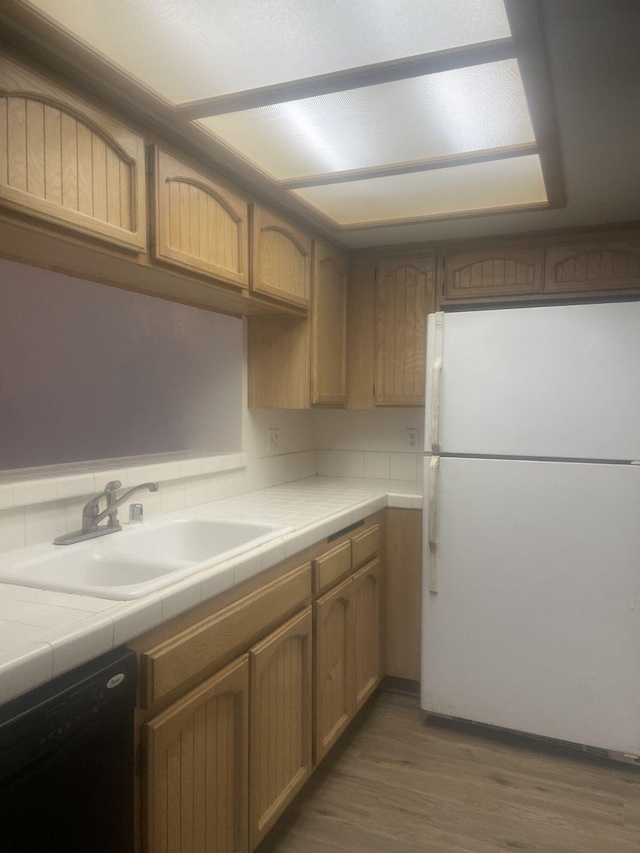 kitchen with sink, black dishwasher, white refrigerator, and tile counters