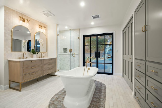 bathroom with a shower stall, a freestanding bath, double vanity, visible vents, and a sink