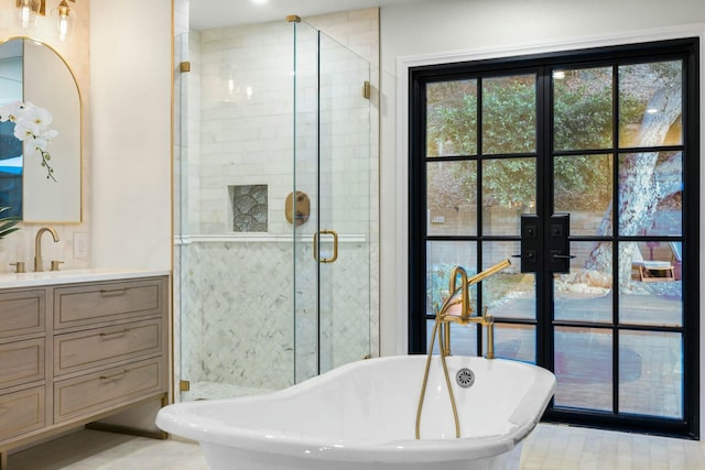 bathroom with a soaking tub, vanity, a stall shower, and french doors
