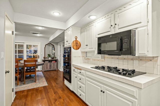 kitchen featuring white cabinets, decorative backsplash, tile counters, and black appliances