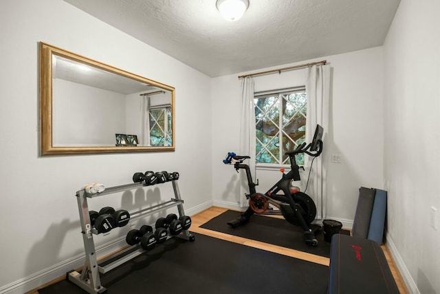 workout area featuring a textured ceiling and baseboards