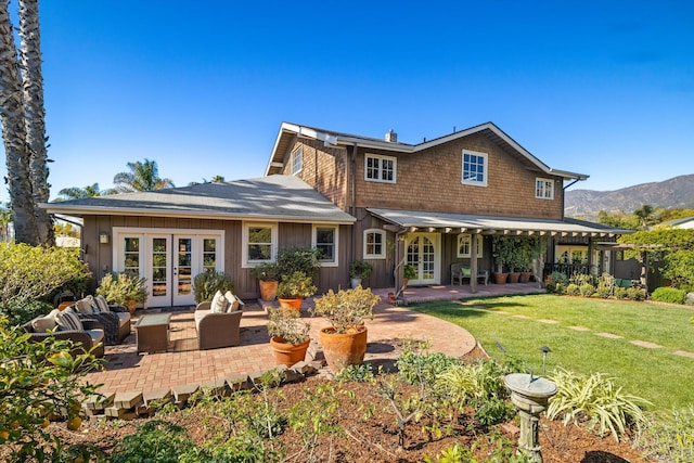 back of house with french doors, a lawn, a mountain view, an outdoor living space, and a patio