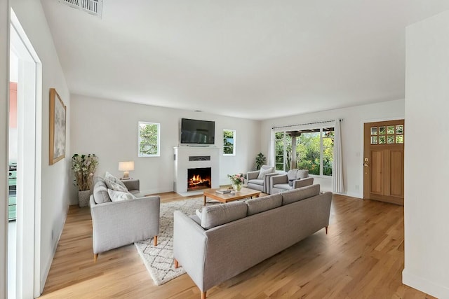 living room with a wealth of natural light, visible vents, and light wood-style flooring