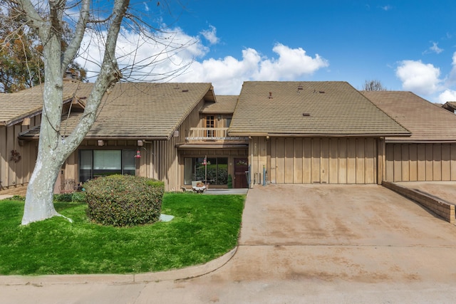 view of front of property featuring board and batten siding, a balcony, and a front lawn