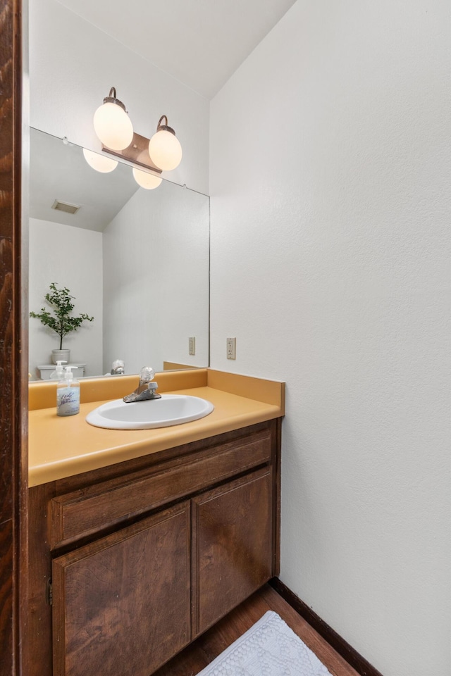 bathroom featuring visible vents, wood finished floors, vanity, and baseboards