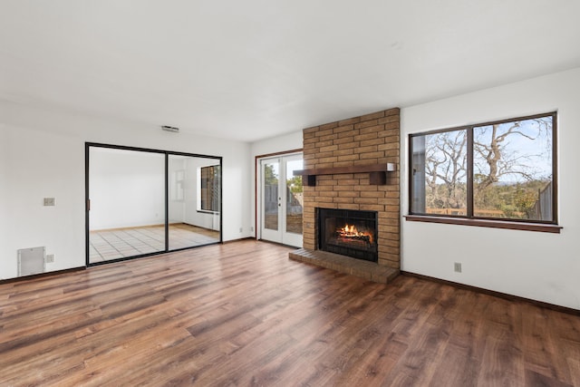 unfurnished living room with visible vents, baseboards, wood finished floors, french doors, and a fireplace