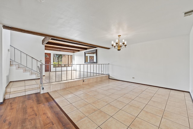 empty room with beam ceiling, a notable chandelier, light tile patterned floors, visible vents, and stairs