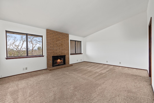 unfurnished living room featuring lofted ceiling, a brick fireplace, carpet flooring, and baseboards