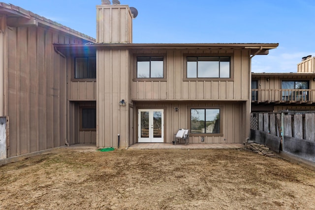 rear view of house with a patio, fence, french doors, board and batten siding, and a chimney