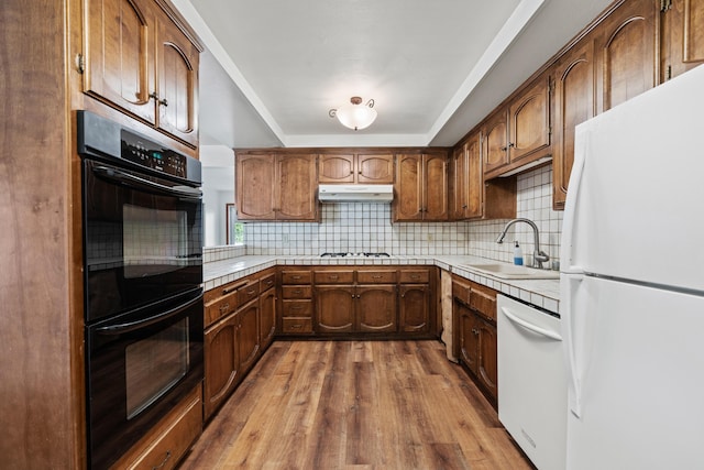 kitchen featuring white appliances, light countertops, a sink, and under cabinet range hood