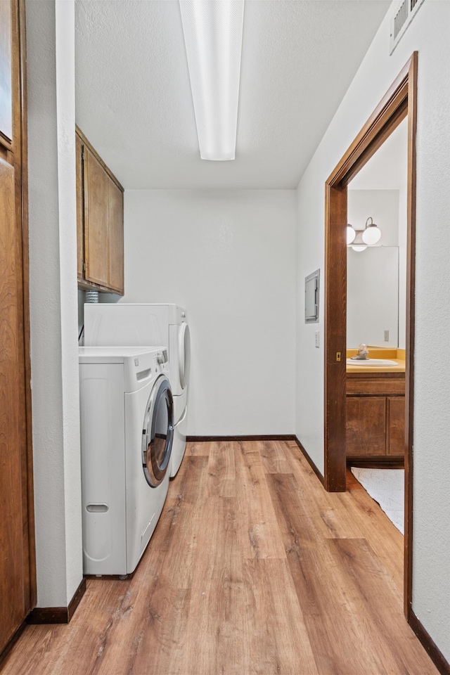 laundry area featuring cabinet space, washing machine and dryer, visible vents, and light wood-style floors