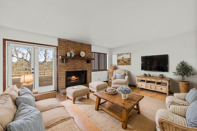 living room featuring french doors, light wood-type flooring, and a fireplace