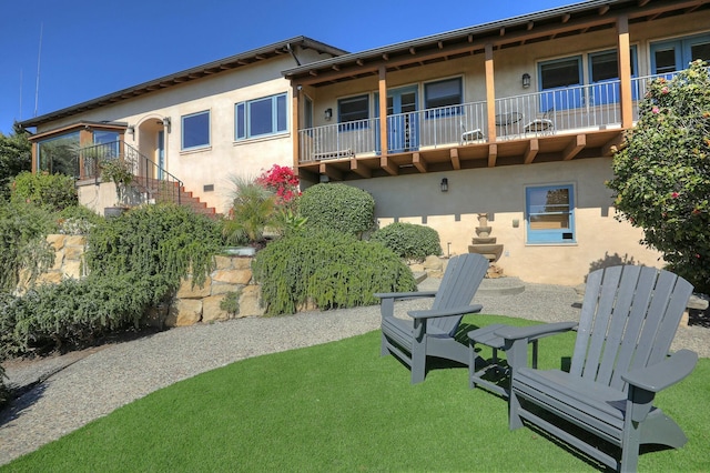 exterior space featuring stairway, a lawn, and stucco siding