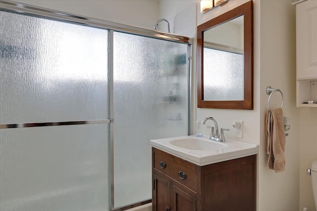 bathroom featuring toilet, an enclosed shower, and vanity