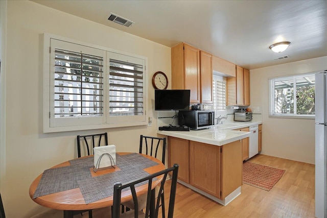 kitchen with light countertops, white appliances, visible vents, and light wood-style flooring